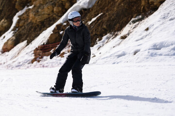 Snowboarder riding downhill on sunny winter day