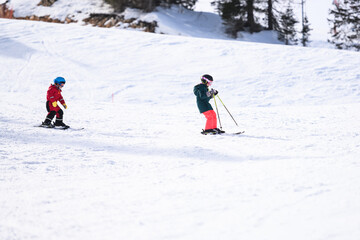 Children skiing downhill on sunny winter day