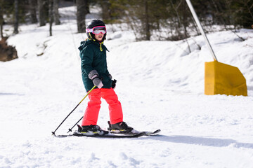 Young girl skiing downhill on sunny winter day