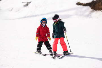 Children skiing downhill on sunny winter day