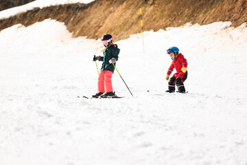 Children skiing downhill on sunny winter day