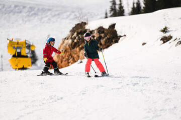 Children skiing downhill on sunny winter day