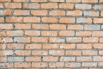 Exposed brick wall showcasing a distressed pattern of old peach paint flaking over grey tones, highlighting the rugged texture and historical impact of time on building materials