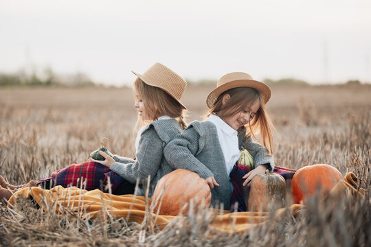 Twin girls enjoying a peaceful afternoon in a pumpkin patch during autumn season