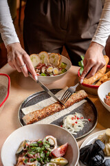Woman cutting Georgian lula kebab with fork and knife