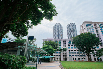 A modern urban landscape featuring high-rise residential buildings, a covered walkway, and lush...