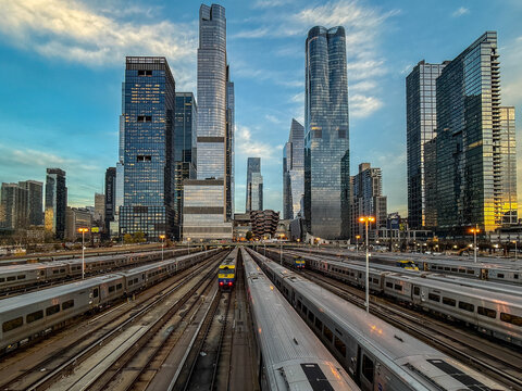 View of trains aligned perfectly beneath a symphony of shimmering skyscrapers piercing the vast sky, reflecting the city's pulse, Hudson Yard, New York, United States.