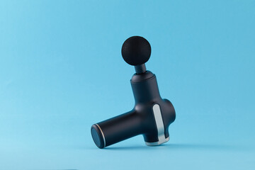 Body massager isolated on blue background. Professional therapeutic shock massage gun for sports and relaxes.