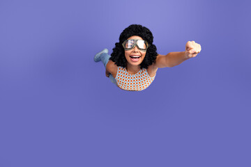 Young woman with curly hair posing confidently against a purple background wearing casual fashion...