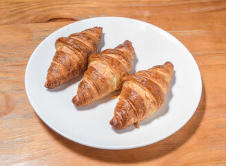 Golden Brown Classic French Croissants on a White Plate on a Wood Table side view of European food