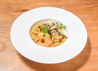Seafood Pasta Spaghetti with Shrimp, Mushrooms, and Parmesan in Cream Sauce in plate on wooden table side view of Italian cuisine