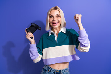 Happy young woman celebrating victory with a game controller in casual style against a colorful...