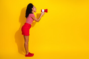 Obraz premium Fashionable young woman with megaphone on yellow background promoting with enthusiasm and style