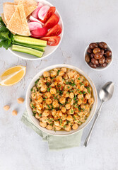 Levantine balila or msabah made with warm chickpeas, olive oil and spices and fresh vegetables on white background