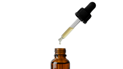 A drop of yellow essential oil falling from a glass dropper

