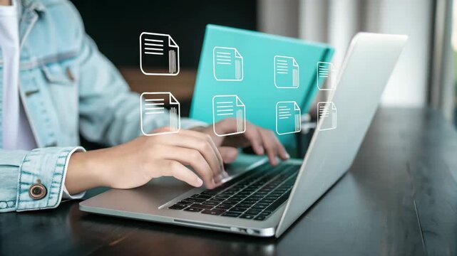 Person typing on a laptop with document icons floating in the air near a blue folder behind it