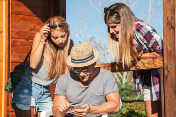 Young friends gathering and viewing a smartphone screen outdoors in summer