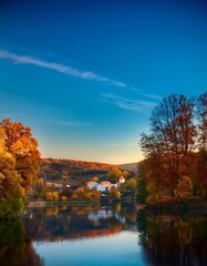 Landscape and trees, romantic evening in the lake during sunset with blue sky; flying over 
