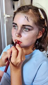 A beautiful girl with blue eyes in the frame, who gets scary makeup for Halloween