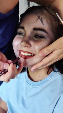A beautiful girl with blue eyes in the frame, who gets scary makeup for Halloween