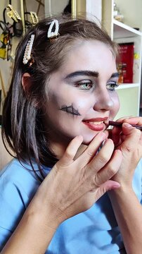 A beautiful girl with blue eyes in the frame, who gets scary makeup for Halloween