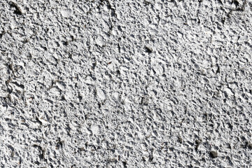 Fototapeta premium Rough gray plaster texture background. Cement wall surface with uneven grain structure. Grunge pattern of construction material for building industry. Abstract solid wall detail.
