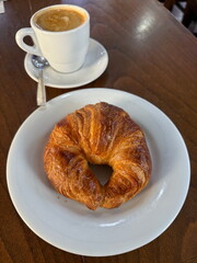 Classic French pastry croissant with hot cappuccino in a white cup, cozy morning atmosphere on wooden tabletop.
Good morning, tasty breakfast