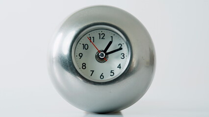 Metal clock ticking white studio space closeup. Hour and minute hands moving 