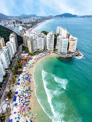 Vista aérea de dia ensolarado com muitos turistas na Praia de Pitangueiras no litoral paulista, Guarujá. 