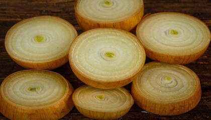 Sliced onions, stacked on rustic wooden background, show layers and center point