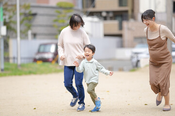 A woman and a child are running in a park. A woman is wearing a brown dress. The child is wearing a green shirt