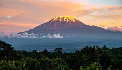 Majestic mountain peak illuminated by a vibrant sunrise glows above lush trees