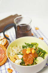 Indonesian Gado-Gado Salad with Peanut Sauce a Colorful and Flavorful Dish Featuring Fresh Vegetables, Tofu, and Tempeh Served in a Bowl and Accompanied by a Beverage Presentation