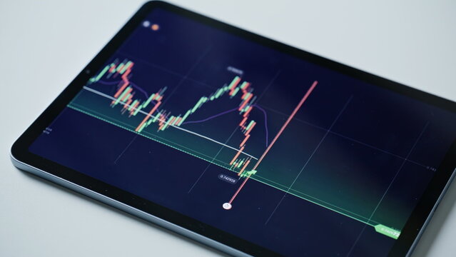 Tablet displaying financial graph with growth indicators rests on office desk