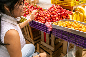 Young woman buying fresh fruit at traditional market