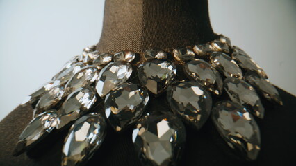 Closeup gemstone necklace arranged on textile bust in quiet room. Jewelry object