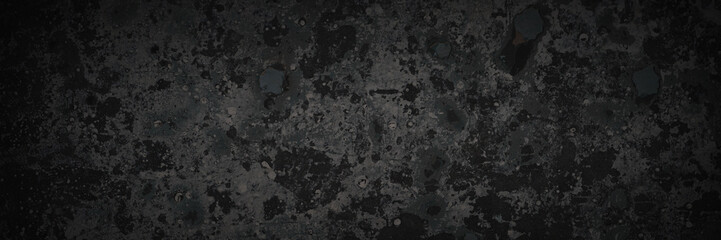 Dark wide panoramic background. Peeling paint on a concrete wall. Dark grunge texture of old cracked flaking paint. Weathered rough painted surface. Patterns of cracks. Darkness background for design.