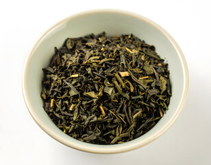 Fototapeta premium Loose leaf green tea leaves in a decorative bowl on a white background