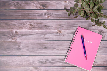 Pink spiral notebook on wooden table. Top view,Minimal workspace with notebook