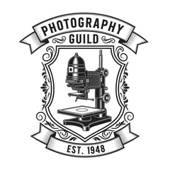 Vintage photography guild emblem featuring a detailed illustration of a darkroom enlarger machine.