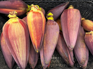 Close-up of fresh banana blossoms in a market basket. Exotic edible flowers used in Southeast Asian cuisine.