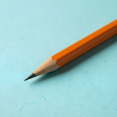 A close-up of a sharpened orange pencil with a dark lead tip, lying diagonally on a textured, vibrant blue-green surface with ample negative space in the foreground. Generative AI.