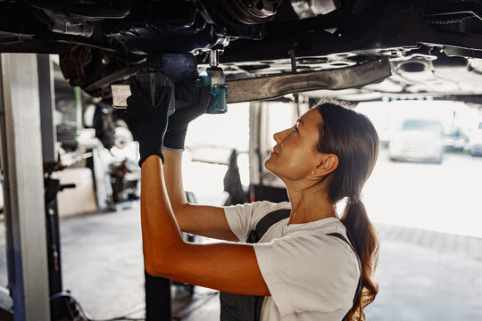 A skilled female mechanic is effectively performing essential maintenance work under a car, showcasing her expertise