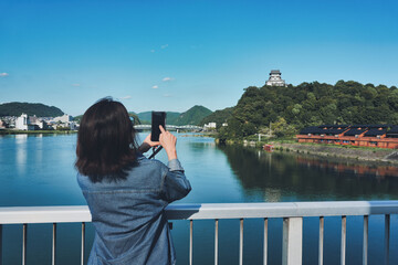 Fototapeta premium 犬山城をスマホで撮影する女性