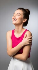 Obraz premium A Beautiful Young Woman with Her Eyes Closed and Laughing with Joy, Embracing Herself in a Studio Portrait