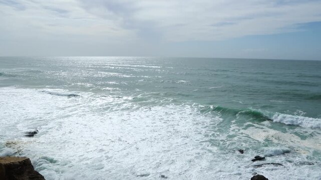 Ocean waves crashing on rocks at Praia das Ma&ccedil;&atilde;s in Sintra, Portugal
