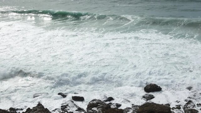 Ocean waves crashing on rocks at Praia das Ma&ccedil;&atilde;s in Sintra, Portugal