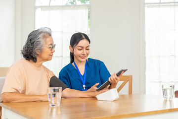 Fototapeta premium Asian woman doctor measuring blood pressure to senior female patient at nursing home. Caregiver or nurse taking care elderly people. Home medical healthcare services and health insurance concept.