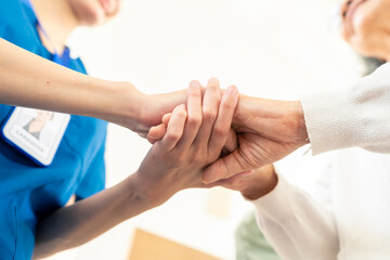 Asian woman caregiver holding senior woman hands and consoling with empathy. Doctor or nurse visit...