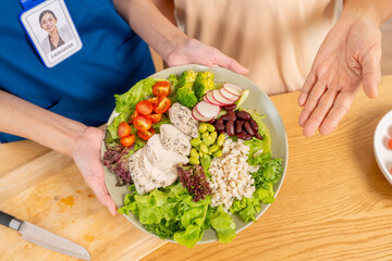 Female caregiver take care and serving healthy food organic salad to senior woman at nursing home. Retirement rehabilitation. Elderly people health, home medical wellness healthcare services concept.